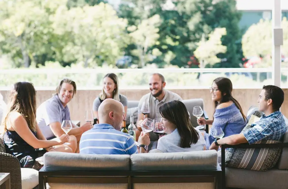 A group of eight seated and enjoying a wine tasting in an outdoor patio setting.