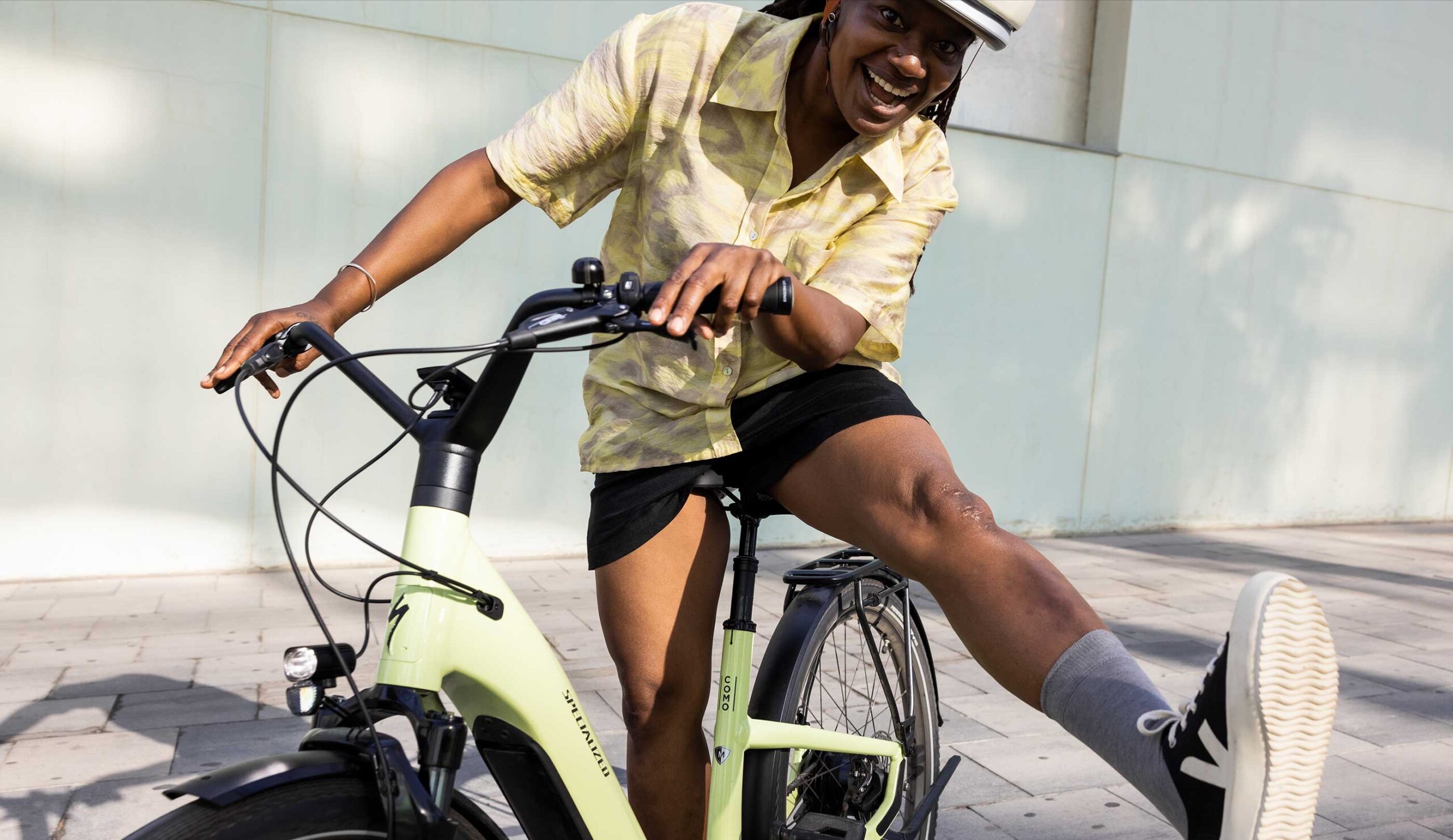 A happy cyclist stands with an electric bike and kicks his foot out